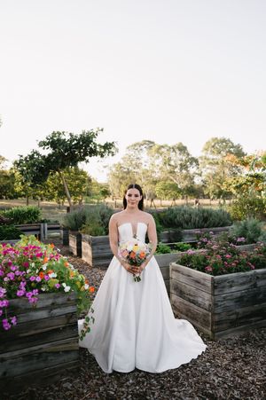Wedding portrait in garden setting with raised flower beds and blooming pink flowers.