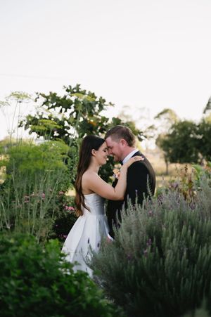 Romantic moment between newlyweds in garden with blooming lavender plants.