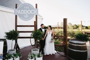 Wedding venue exterior showing rustic signage for 'The Paddock' with wooden beams and barrels.