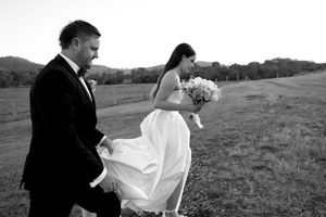 Wedding party celebrating in open field with dramatic mountain backdrop.