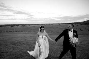 Black and white wedding portrait with couple standing in open field.