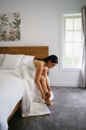 A sequence of artistic bridal preparation photos showing a white dress against a gray carpet in a bright room.