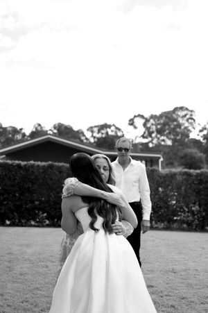 Emotional embrace captured in black and white photography on a grassy field.