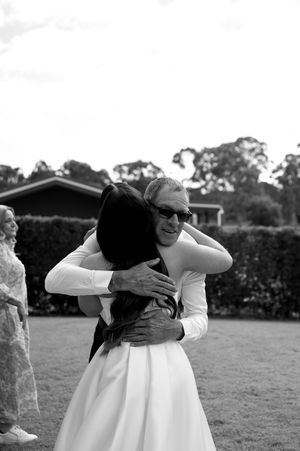 Joyful group hug moment photographed in black and white at an outdoor venue.