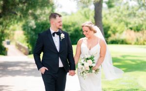 Wedding couple walking together on garden path in formal attire.
