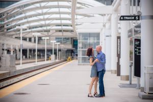 Modern engagement photos at a bright, minimalist train station platform.