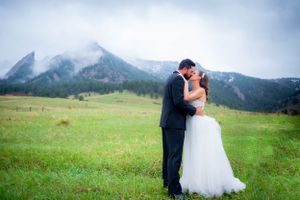 Romantic couple embraces in a scenic mountain meadow with dramatic peaks in the background.