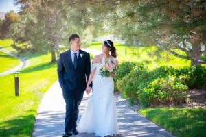 Couple walking along a tree-lined path in a lush garden setting.
