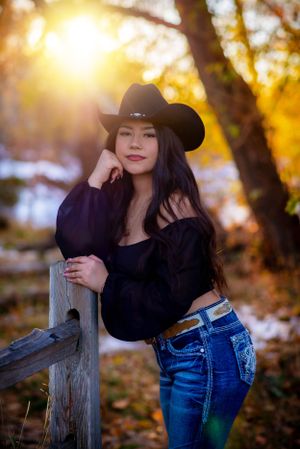 Western style portrait with cowboy hat against golden sunset in autumn setting.