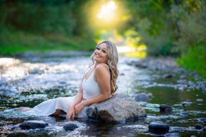 Artistic sunset photoshoot by a creek with golden light filtering through trees.