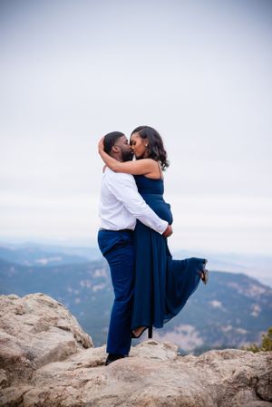 Couple sharing an intimate moment on a rocky mountain overlook with sweeping valley views.