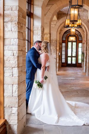 A couple shares an intimate moment in an elegant stone archway corridor with hanging lanterns.