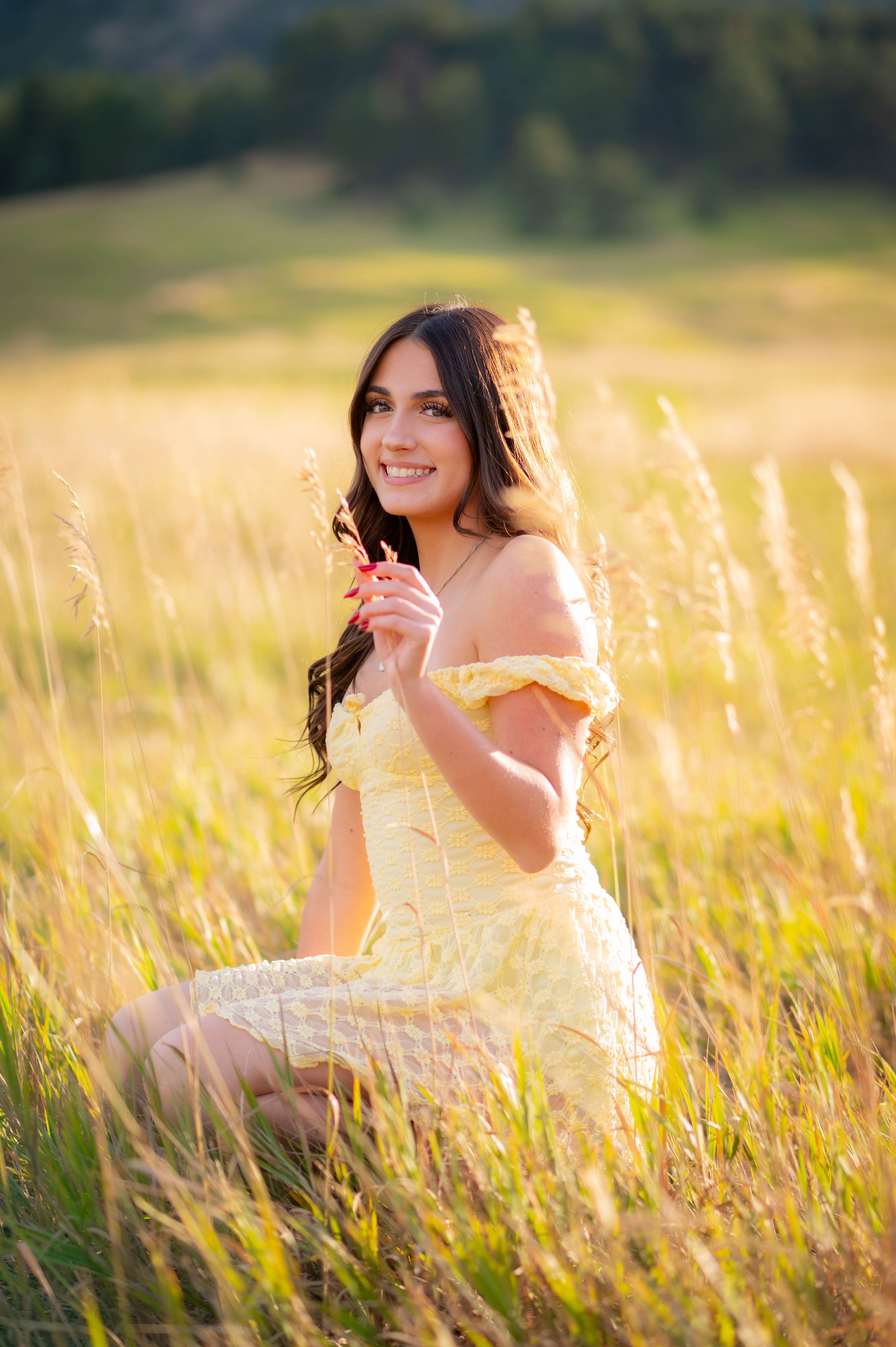 A yellow sundress-clad figure sits in a golden sunlit meadow with tall grass during golden hour.