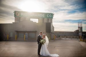 Wedding portraits taken in front of an industrial warehouse building at sunset.