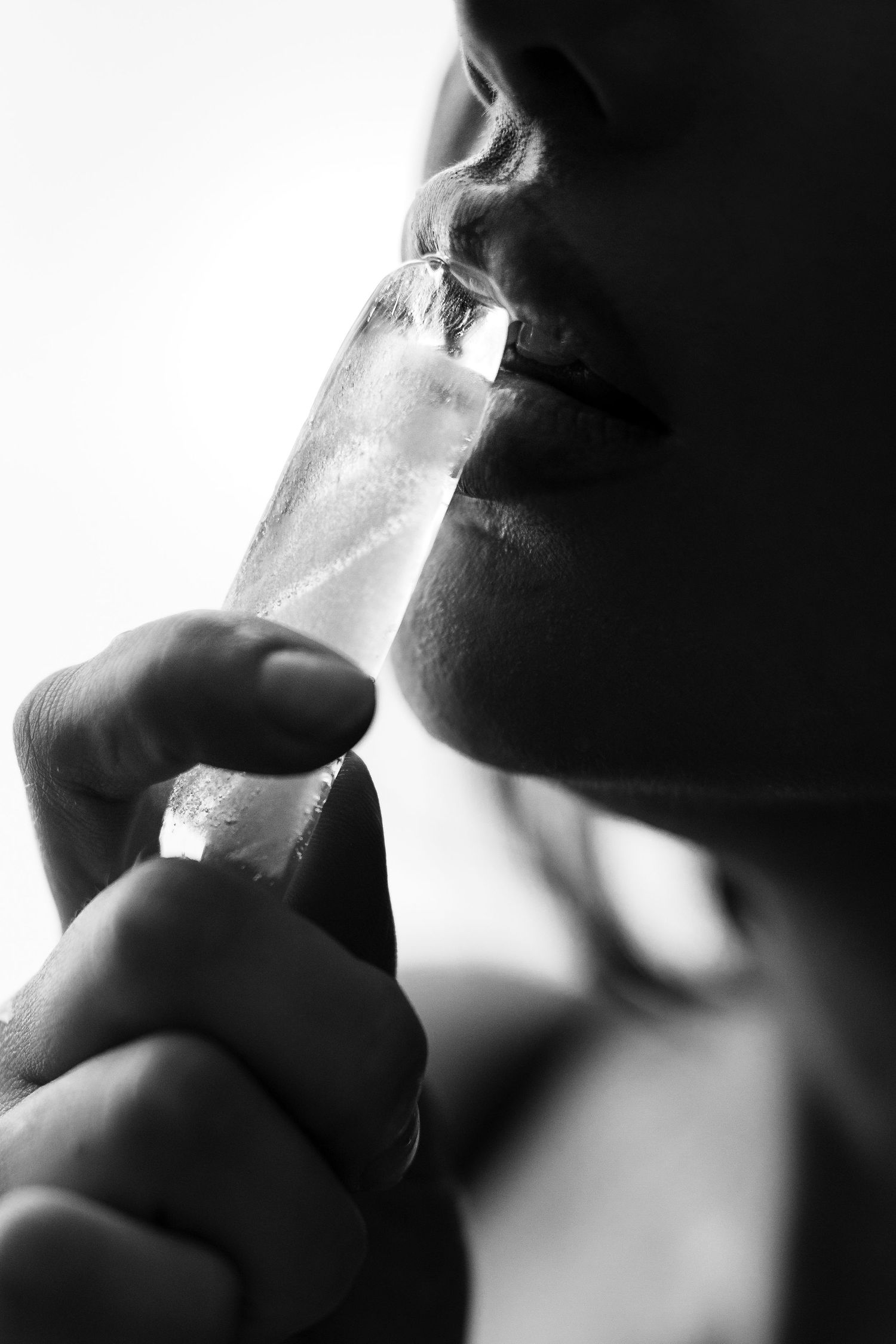 Artistic black and white close-up profile view of someone smoking a cigarette in moody lighting.