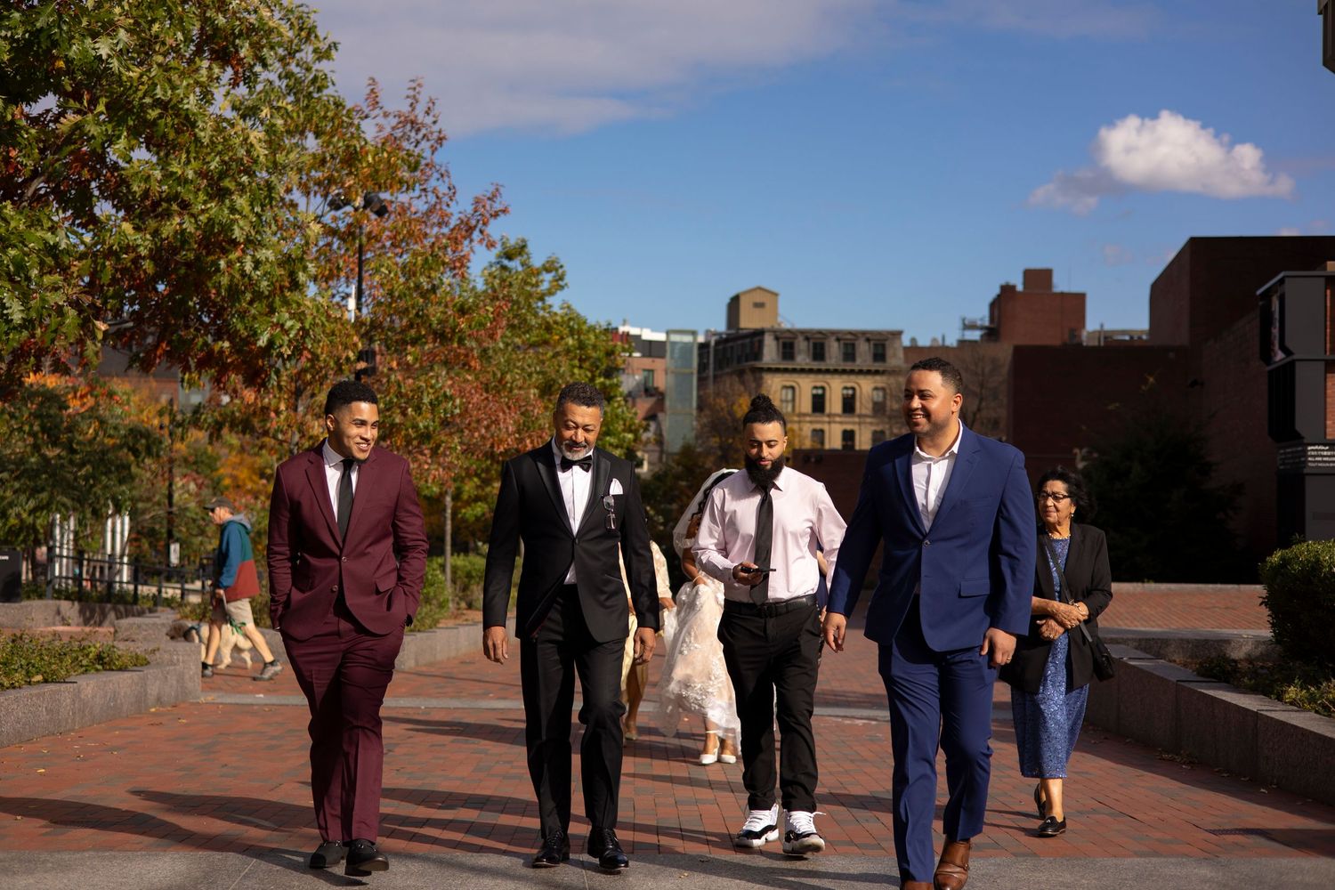 People walking and conversing on a brick paved path during a sunny autumn day.