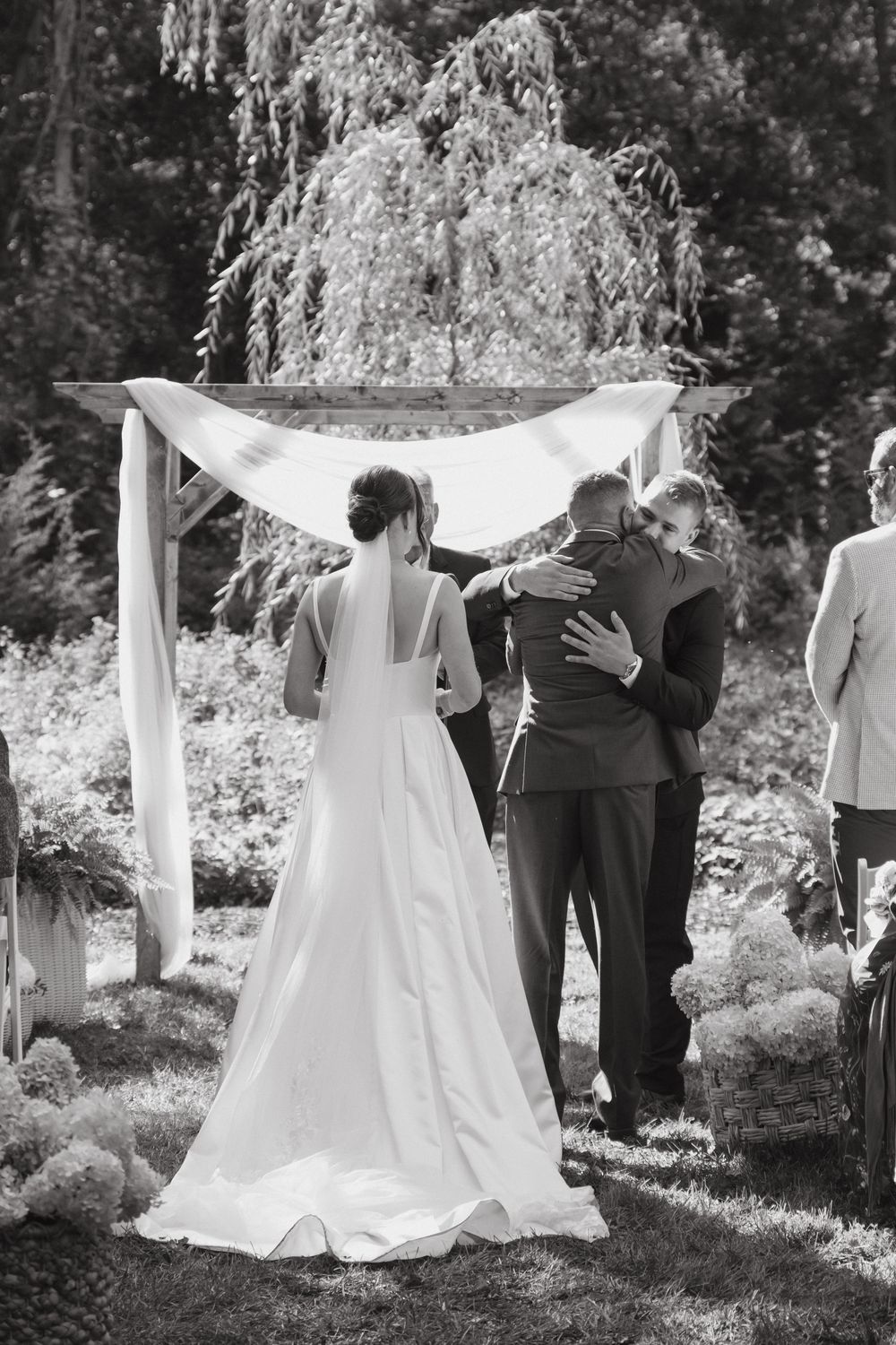 A sequence of wedding ceremony photos showing white dresses and linens blowing in the wind against a wooded backdrop.