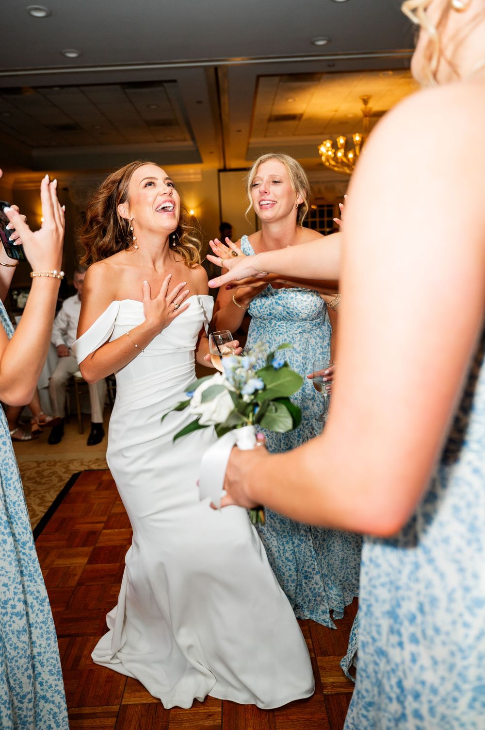 Wedding party dancing and celebrating on wooden dance floor with floral decorations.