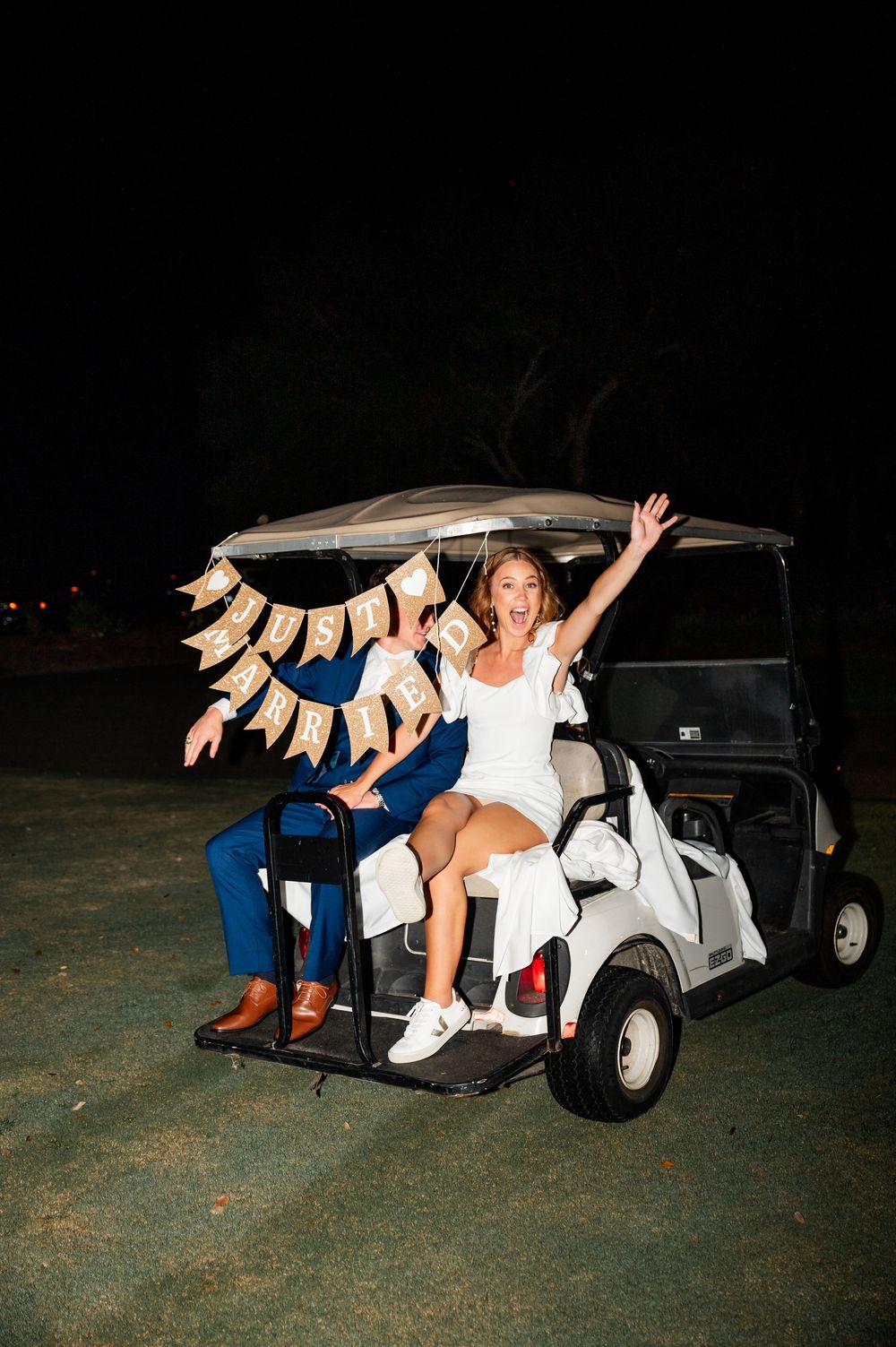 Couple celebrating in a golf cart decorated with flip flops at night.