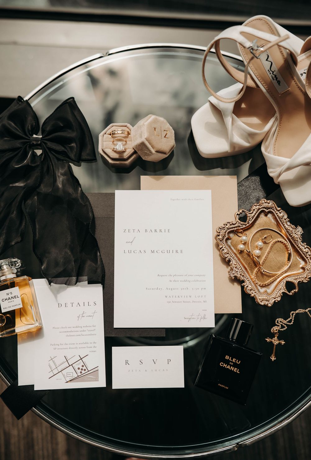 Wedding flat lay featuring Chanel perfume, invitation suite, bridal heels, and gold accessories.