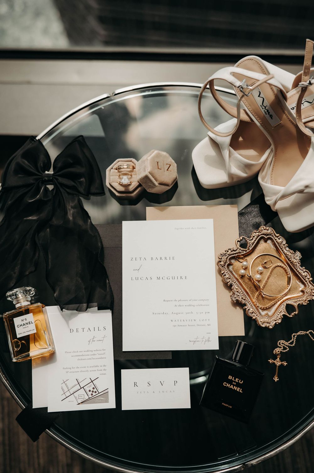 Luxury wedding flat lay with Chanel perfume, invitation suite, heels, ring box, and gold jewelry.