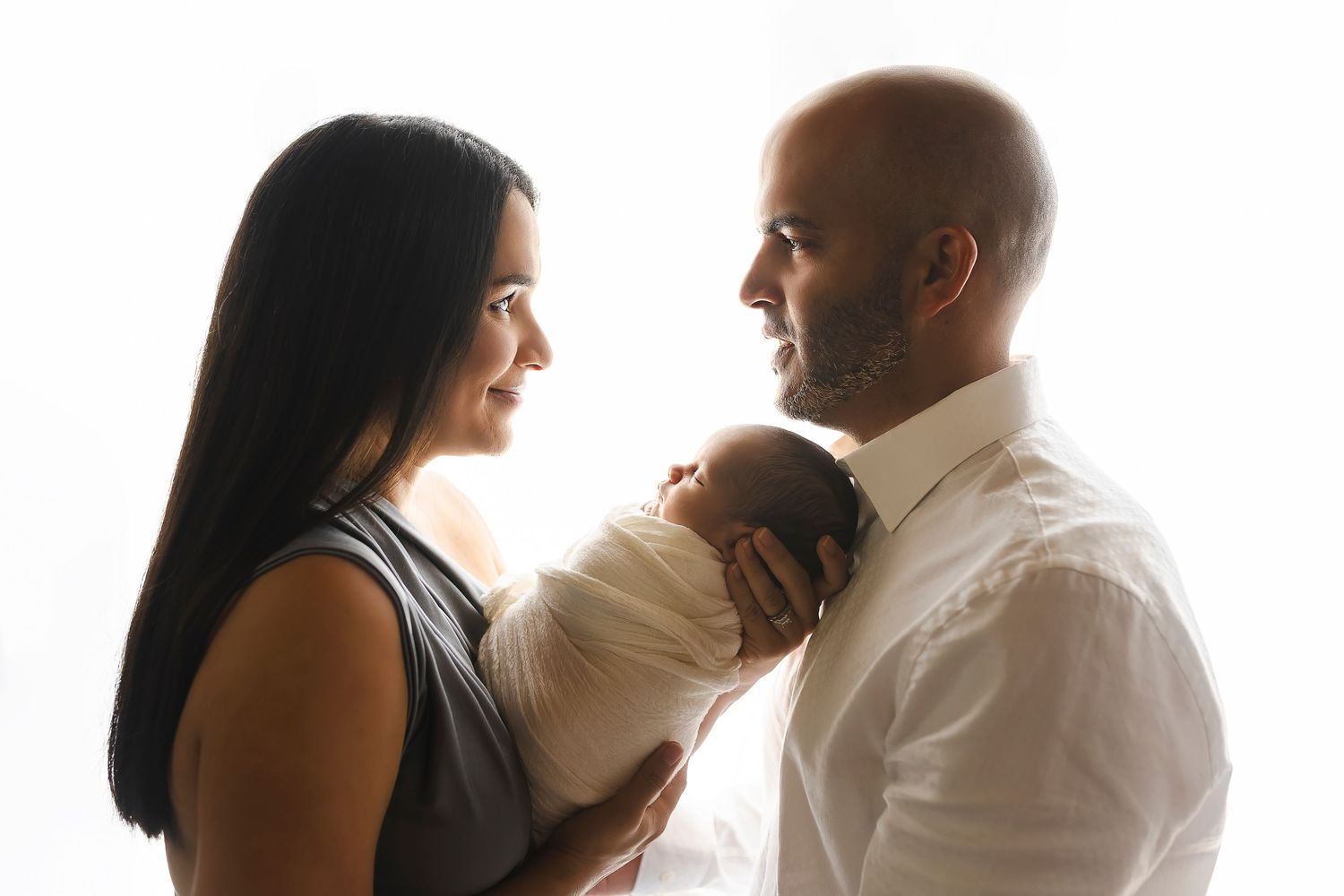 Fotografia de padres y bebe en contra luz padres primerizos