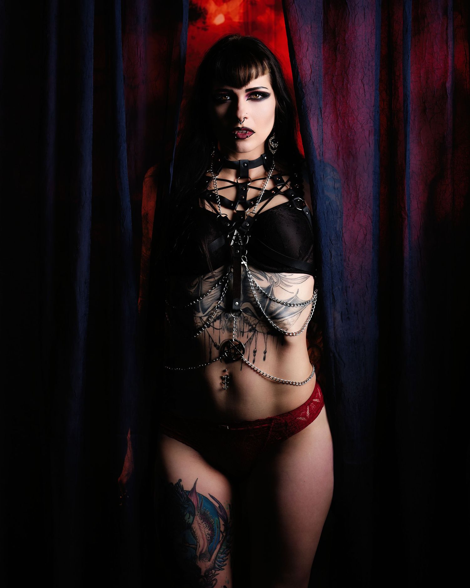 David G Holt Photography - A gothic-style portrait in dark red and black tones featuring dramatic lingerie and tattoo art in moody lighting.