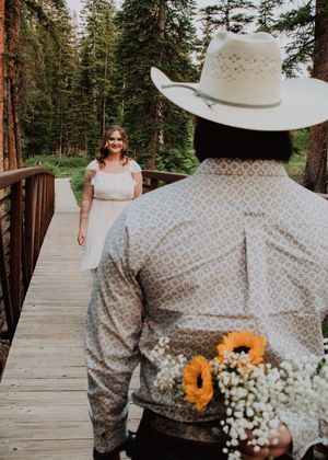 man holding flowers behind his back to surprise woman walking towards him