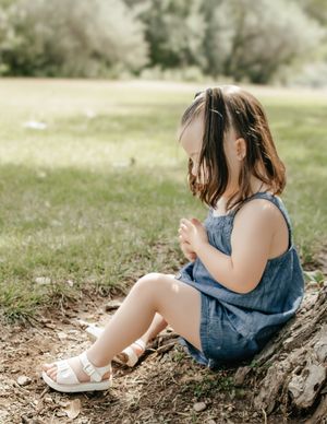 little girl sitting on ground playing with dirt and rocks