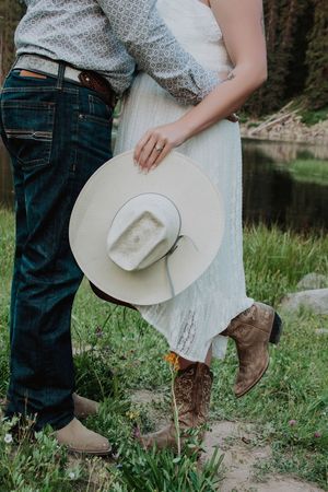 detail shot of couples feet embracing each other holding a hat low