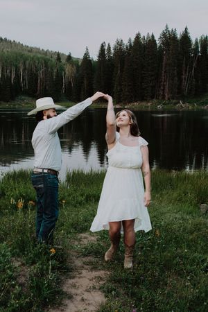 couple twirling and dancing near a lake at dusk