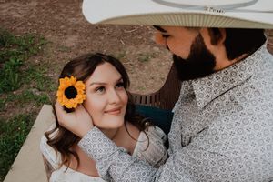 man placing flower in woman's hair while she is laying across his legs looking up at him