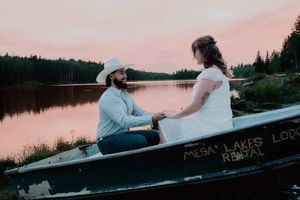 couple sitting in boat looking and smiling at each other near a lake at sunset