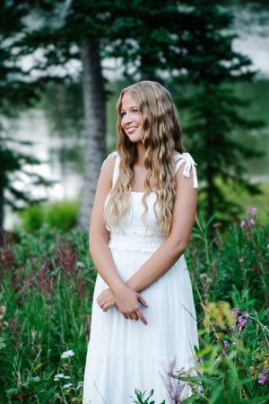 female standing posing smiling in a field of flowers