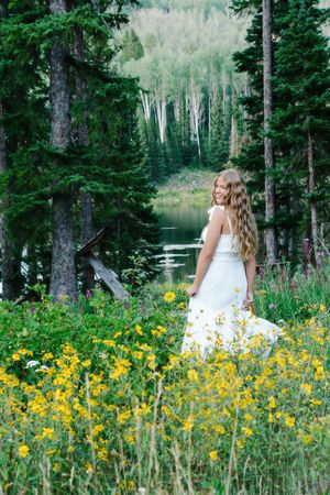 female twirling in a field of flowers with body of water in background