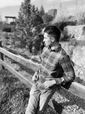 Male senior photoshoot with rustic fence and natural landscape background