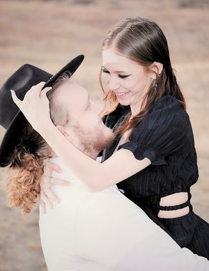 male holding female up while female fixes male's hat