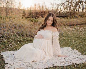 Maternity photoshoot with expecting mother sitting on blanket outdoors