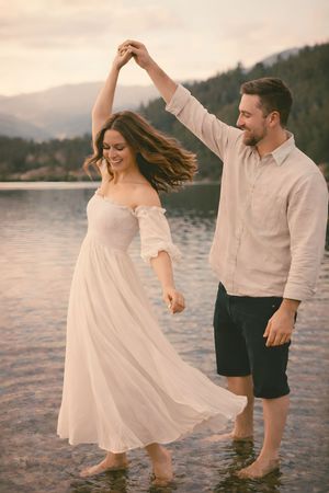 Romantic engagement session with couple twirling in water at sunset