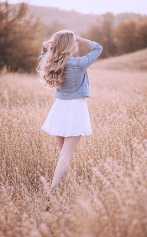 Outdoor senior session featuring young woman in white dress and denim jacket