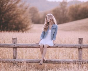 High school senior photoshoot with rustic fence and natural landscape