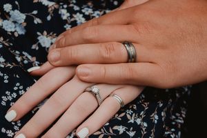 a close up picture of a couples hands with wedding bands on their fingers