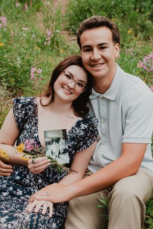 a couple sitting next to each other smiling holding a picture of their cat
