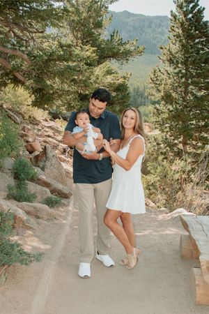 a family posing on a path next to each other with dad looking down at baby and mom smiling
