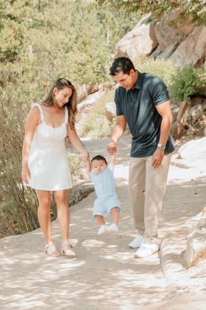 a family walking along a path swinging baby
