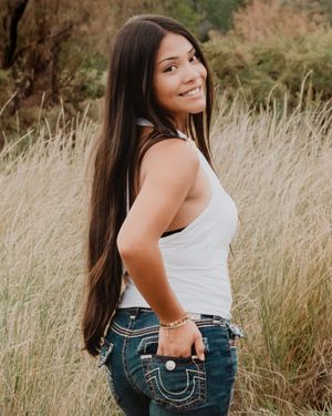 female standing looking over shoulder smiling with hand in back pocket
