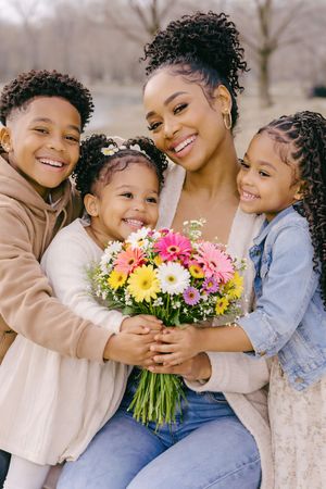 Family photography with mother and children smiling and holding flowers