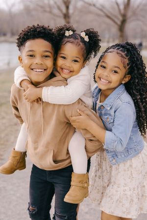 Three siblings smiling and hugging during an outdoor family photoshoot