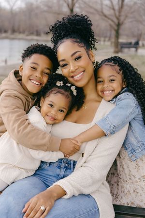 Mother and three children smiling and hugging during an outdoor family photoshoot