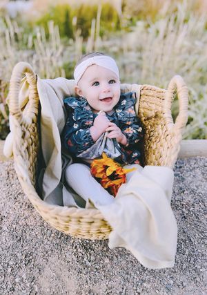 Outdoor baby photoshoot featuring cozy basket and soft neutral tones